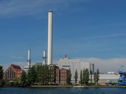 Industrial plant with chimneys and red brick buildings on the waterfront under a clear sky,