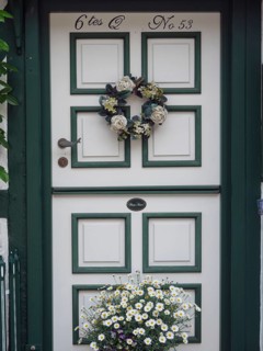 A beautifully decorated door with a wreath of flowers and a flower box underneath, Schleswig,