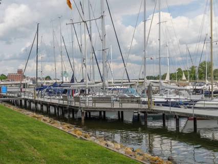 Sailboats dock at the marina in a partly cloudy sky with manicured lawn, Kappeln,