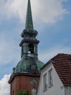 Historic church tower with green roof and clock next to a building, Arnis, Schleswig-Holstein,