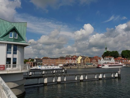 View of the town and harbour with boats and a bridge under a cloudy sky, Kappeln,