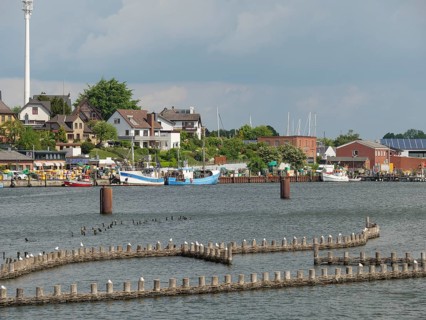 View of the harbour with fishing boats and buildings along the shore under a cloudy sky, Kappeln,