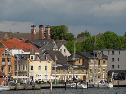 Town view with historic buildings, chimneys and boats on the waterfront under a cloudy sky,