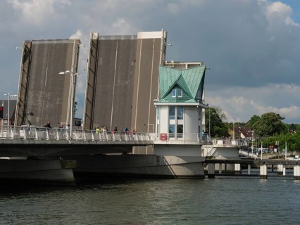 An open bridge next to a small watchtower over a river under a cloudy sky in a town, Kappeln,