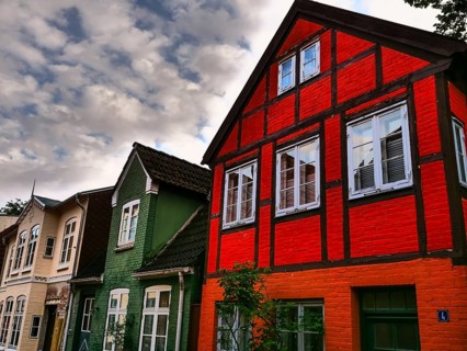 Cornice decorated half-timbered houses in red and green under a cloudy sky, Eckernförde,