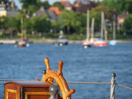 Nautical steering wheel of a ship with a view of the water and the coast, Eckernförde,