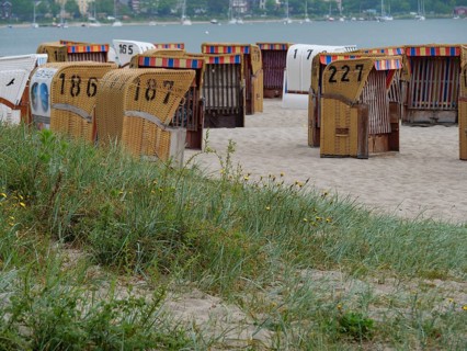 Beach with numbered beach chairs and views of the sea and surrounding coastline, Eckernförde,