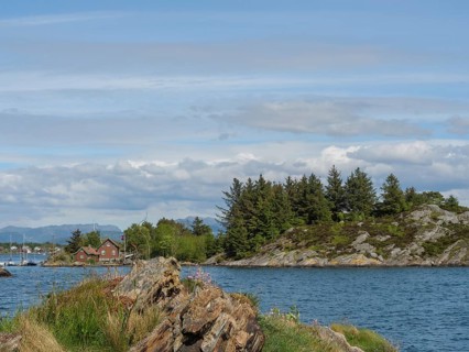 Panorama of a coastal landscape with sea, islands and rocky shores under a blue sky with clouds,