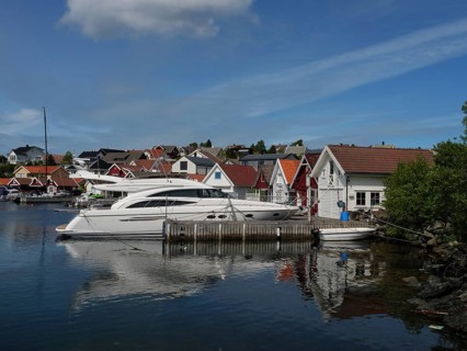 White yachts in the harbour in front of houses with red roofs. Calm water reflects the boats and