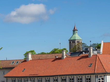 Historic tower and building with tiled roofs under a blue sky with light clouds, Stavanger, Norway,