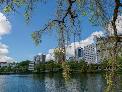 Urban building backdrop by a lake, surrounded by trees and blue sky with clouds, Stavanger, Norway,