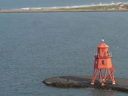 Red lighthouse on a pier, on a calm day with a wide sea view, Newcastle, England, Great Britain
