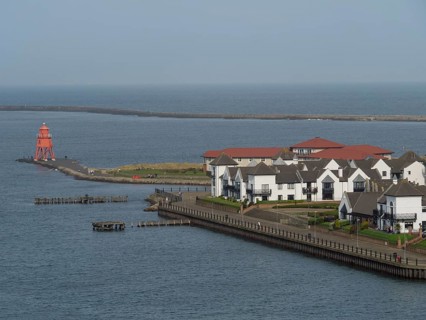 Coastal town with white houses, lighthouse and promenade, view of the blue sea, Newcastle, England,