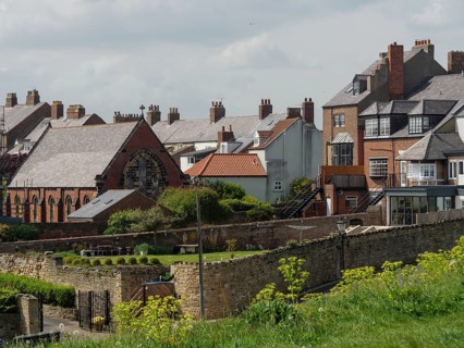 Several historic brick houses with private gardens in an urban setting on a slightly cloudy day,