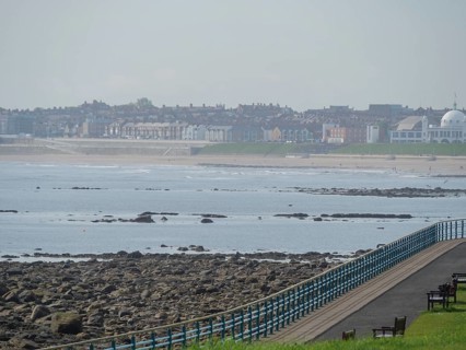 A stretch of coastline with a promenade and a view of a town in the background, Newcastle, England,