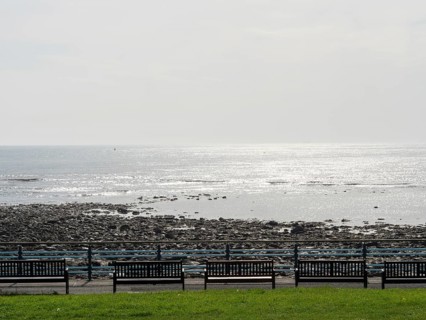 Panoramic view of the sea with benches in the foreground and shiny water surface, Newcastle,