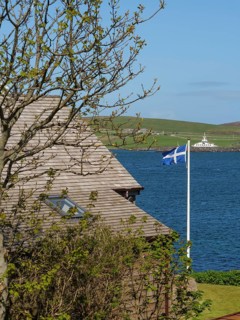 View of a coastal landscape with a house roof, a tree and a Scottish flag, Lerwick, Shetlands,