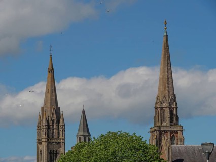 Buildings with high church towers and gothic architecture under a slightly cloudy sky, inverness,
