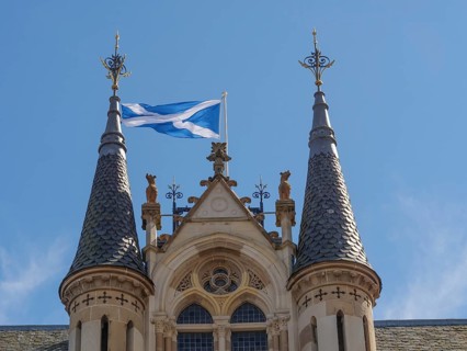 Close-up of a castle with Scottish flag, distinctive towers and detailed architecture under a clear
