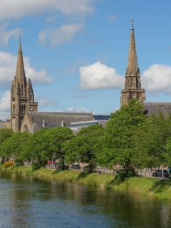 Church buildings and other architectural structures on the banks of a river, surrounded by trees