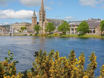 City view along the river with prominent churches and buildings and a bridge in the background,
