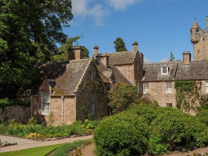An old building with castle and garden, surrounded by stone walls and dense vegetation, inverness,