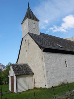 White church with tower under a clear sky, surrounded by green nature and mountains, Eidfjord NOR 3