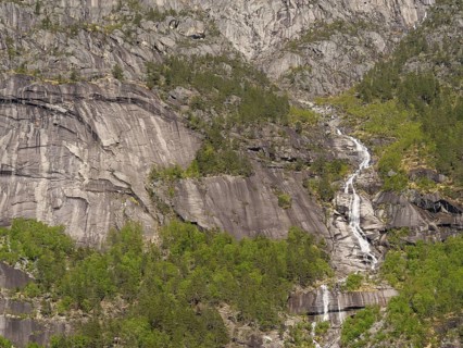 A high waterfall cascades down between steep rocks and wooded cliffs, Eidfjörd, Norway, Europe