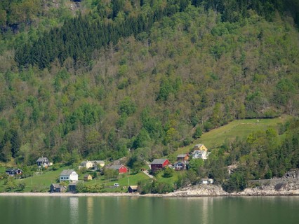 View of country houses at the edge of a forest, reflected in the still water of a lake, Eidfjord,