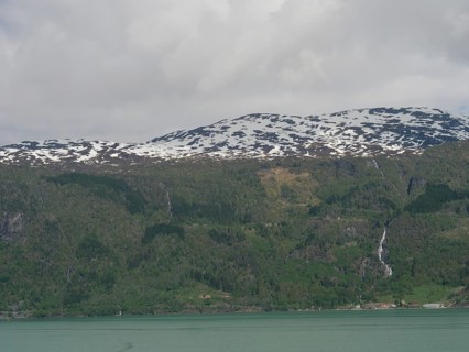 View of snow-capped mountains with waterfalls and a calm lake below, Eidfjord, Norway, Europe
