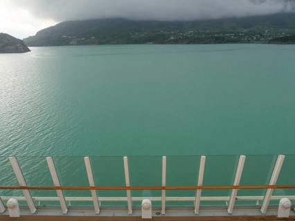 View of calm, greenish water and surrounding misty mountains, seen from a boat, eidfjord, norway