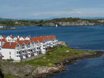 White houses with red roofs on the coast. Tranquil seascape with sailing boat and rocks in the