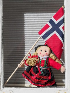 A doll in traditional traditional costume holds a Norwegian flag and stands in a window, Stavanger,
