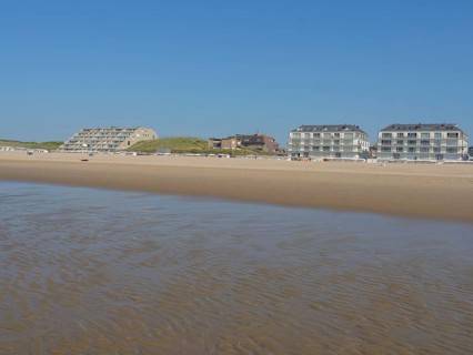 Building on a vast sandy beach with calm sea and blue sky in the background, de haan, belgium