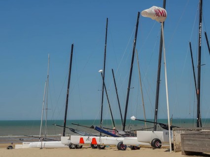 Several sailing boats on the beach, the sea and a clear blue sky in the background, de haan,