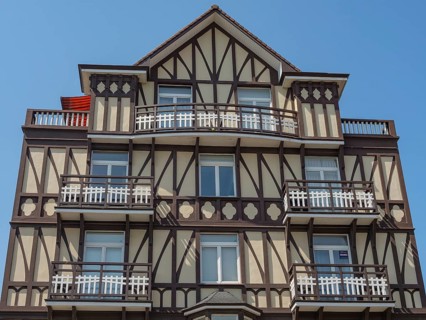 Facade of a multi-storey half-timbered house with balconies on a sunny day, de haan, belgium