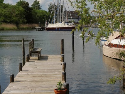 Wooden jetty on the water with moored boats and trees in the background, Arnis, Schleswig-Holstein,