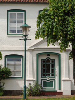 Charming white house with green accents and surrounded by lush greenery, Arnis, Schleswig-Holstein,