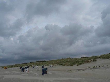 Empty beach with beach chairs, large dunes and dark grey clouds in the sky, juist, east frisia,