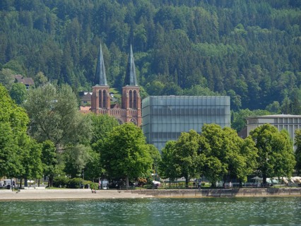 Two church towers and a modern building in a green, wooded setting by the lake, Lindau, Lake