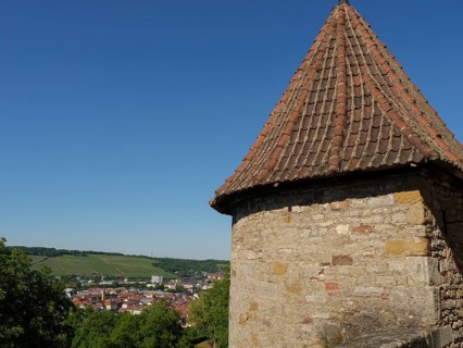 Historic stone tower and wall with a view of the village and surrounding vineyards in the sunshine,