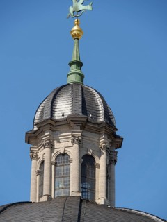 Detailed view of a historic dome with decorative elements and windows under a blue sky, Würzburg,
