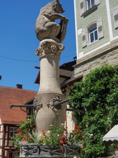 Stone fountain with a lion sculpture and flowers in front of a historic building, Meersburg, Lake