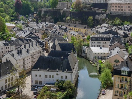 Old town scene with narrow houses, a river and wooden hills in the background, Luxembourg City,
