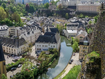 View of an old town with historic buildings by a river and green surroundings, Luxembourg City,