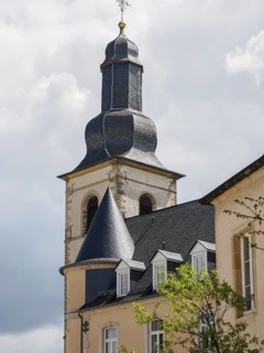 A church tower and a historic building under a bright, cloudy sky, Luxembourg City, Luxembourg,