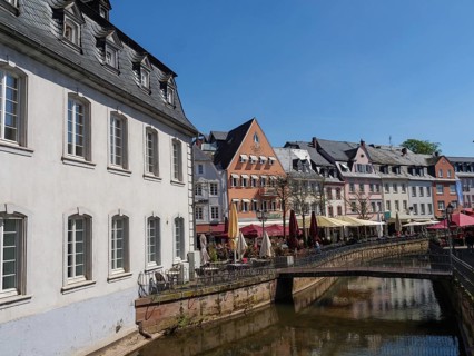 Scenic view of an urban scene with river, buildings, a bridge and sunshades along a canal,