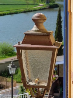 Close-up of an old street lamp next to a river, surrounded by nature, Saarburg, germany