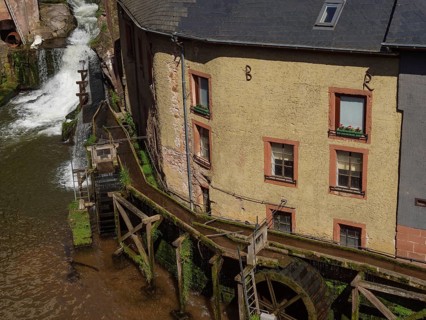 Watermill with old buildings on the river, detail of the wooden structure and wheels, Saarburg,