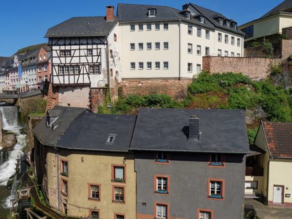 Historic buildings and half-timbered house next to a river in a picturesque town view, Saarburg,